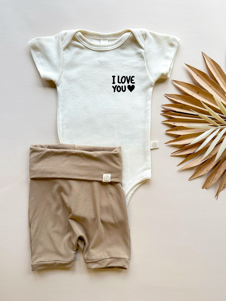 organic cotton baby clothing bodysuit with cute i love you heart screen printed graphic paired with almond tan color elastic free hypoallergenic bamboo baby shorts, green baby clothing, ethical baby brand, sustainable natural fibers, eco-friendly